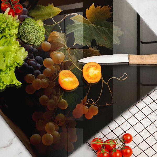 Tábua de cortar de vidro Um copo de vinho e uvas