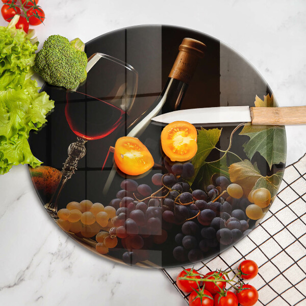 Tábua de corte de vidro Um copo de vinho e uvas