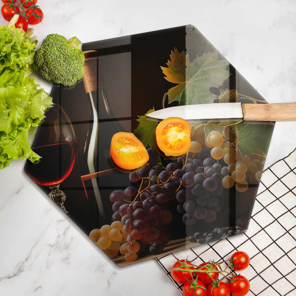 Tábua de corte de vidro Um copo de vinho e uvas